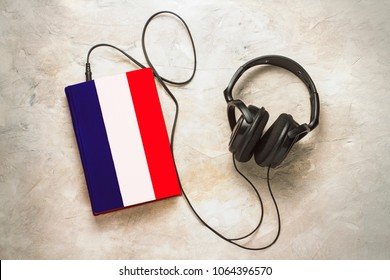 Headphones and book. The book has a cover in the form of a flag of France. Concept audiobooks. Learning languages. French language. - Powered by Shutterstock