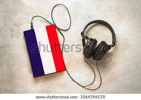 Headphones and book. The book has a cover in the form of a flag of France. Concept audiobooks. Learning languages. French language.