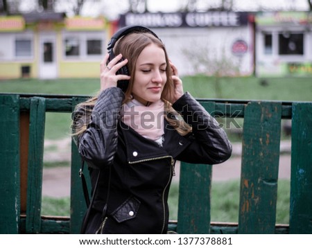 The headphones girl listens to music and sits in the city
