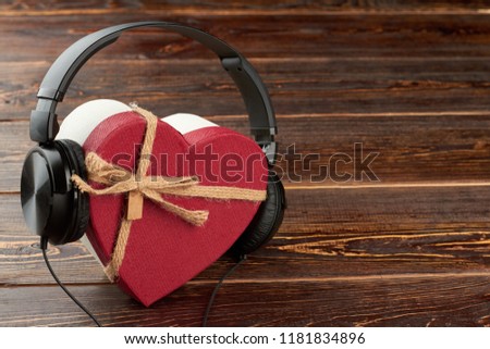 Headphones and heart-shaped gift box. Earphones and red gift box with copy space. Music gift concept.