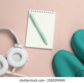 Headphones, Notebook And Blue Sports Shoes On Pink Background. Training Plan. Sport Concept. Running  Active Lifestyle Accessories. Top View