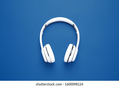 Headphones on bright background, top view. Color of the year 2020 (Classic blue)