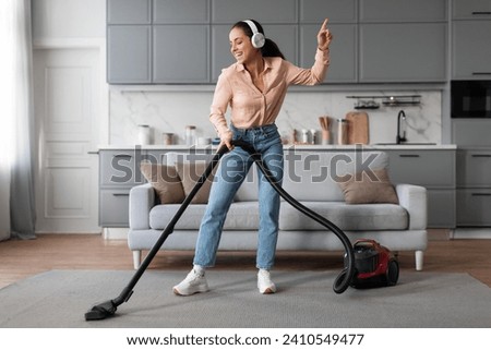 With headphones on, joyful woman dances while vacuuming her living room, turning mundane chore into an enjoyable and rhythmic experience