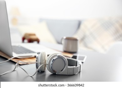 Headphones, phone and laptop on white table against defocused background - Shutterstock ID 366639842