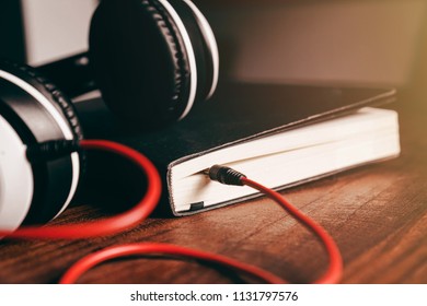 Headphones are placed on the book.Listening skill.Converting the contents of a book into an audio file.Listening to podcasts.