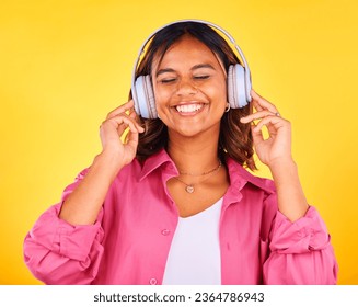 Headphones, smile and young woman in a studio listening to music, playlist or radio for entertainment. Happy, technology and female model from Mexico streaming a song or album by yellow background. - Shutterstock ID 2364786943