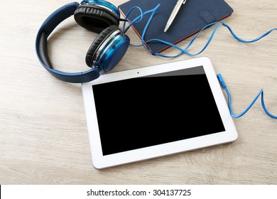 Headphones with tablet and notebook on wooden table close up - Powered by Shutterstock