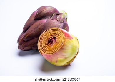 Heads of raw fresh purple romanesco artichoke vegetable heads and pilled hearts ready to cook solated on white background - Shutterstock ID 2245303667