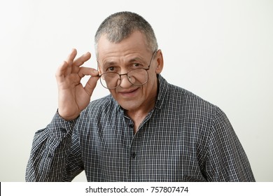 Headshot Of Attractive Smoothly Shaven 60 Year Old Retired Man With Grey Hair Adjusting His Stylish Eyeglasses, Going To Watch Series On TV Or Read Newspaper. People, Age, Optics And Eyewear Concept