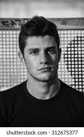 Headshot Of Attractive Young Man Looking At Camera, Against Grid Background, Black And White Shot