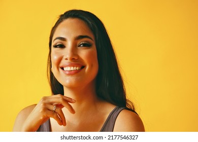 Headshot Beauty Shot Of Hispanic Latina Woman Smiling Young Adult With Black Long Hair And Tank Top In Front Of Yellow Background Looking At Camera Studio Shot