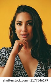 Headshot Beauty Shot Of Sensual Thoughtful Hispanic Latina Woman Young Adult With Black Long Hair Hand On Chin And Dress In Front Of Yellow Background Looking At Camera Studio Shot