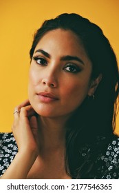 Headshot Beauty Shot Of Sensual Thoughtful Hispanic Latina Woman Young Adult With Hands On Black Long Hair And Dress In Front Of Yellow Background Looking At Camera Studio Shot