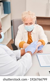 Headshot Caring Nurse Supporting, Comforting Beautiful Older Woman With Blonde Curly Hair At Home. Doctor Touching Mature Patient Hands Close Up. Healthcare Concept, Compassion And Empathy