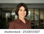 Headshot close up face portrait of young happy smiling Hispanic businesswoman, female company worker or corporate manager, confident business woman entrepreneur looking at camera at work in office.