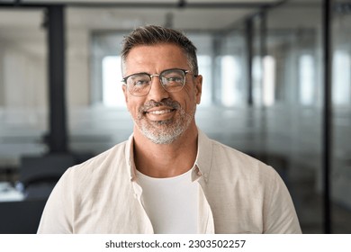 Headshot close up portrait of latin confident mature good looking indian middle age leader, ceo male businessman on blur office background. Handsome hispanic senior business man smiling at camera. - Shutterstock ID 2303502257