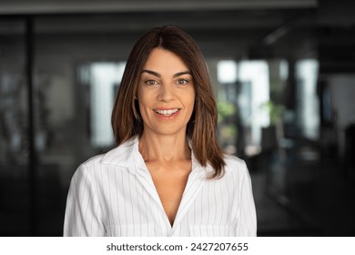 Headshot close up portrait of latin hispanic confident mature good looking middle age leader, ceo female businesswoman on blur office background. Gorgeous beautiful business woman smiling at camera. - Powered by Shutterstock