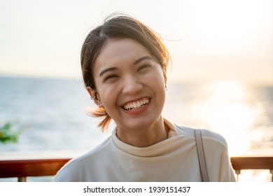 Headshot Close-up Portrait Of A Casually White Dressed, Young Asian Woman Smiling, Authentic People, Standing Alone Outside On Summer Beach, Looking Camera, Smiling Friendly, Candid Photos, Sunset