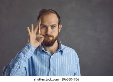 Headshot of confident handsome young caucasian guy showing secret silent gesture asking stop talking keep silence asking be quiet. People emotion and expression face portrait and confidentiality