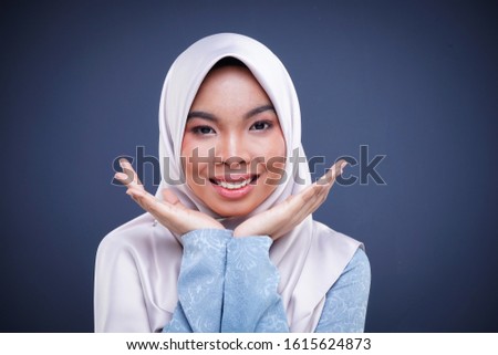 Headshot of a cute Muslim teenager wearing hijab showing various facial expressions isolated on grey background. Landscape orientation.