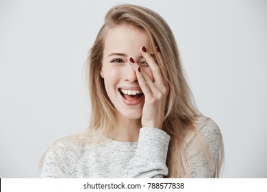 Headshot of cute woman with dark eyes, blonde long hair, happy gentle smile rejoicing her success. Cheerful woman having birthday having pleased expression and pleasure. Face expressions