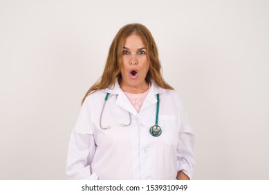 Headshot Of Goofy Surprised Bug-eyed Doctor Woman Student Wearing Medical Uniform Staring At Camera With Shocked Look, Expressing Astonishment And Shock, Screaming Omg Or Wow