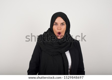 Headshot of goofy surprised bug-eyed muslim woman  staring at camera with shocked look, expressing astonishment and shock, screaming Omg or Wow