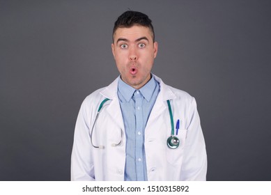 Headshot Of Goofy Surprised Bug-eyed Young Doctor Man Student Wearing Medical Uniform Staring At Camera With Shocked Look, Expressing Astonishment And Shock, Screaming Omg Or Wow