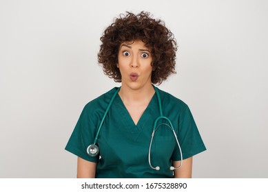 Headshot Of Goofy Surprised Bug-eyed Young Doctor Woman Wearing Medical Uniform Staring At Camera With Shocked Look, Expressing Astonishment And Shock, Screaming Omg Or Wow