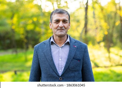 Headshot of happy old mature asian man with black gray hair wearing jacket and shirt smiling positive and looking at camera in park. Senior asian male portrait with retirement concept.