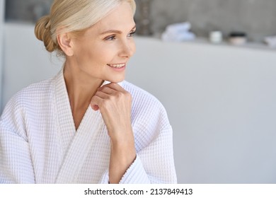 Headshot of happy smiling gorgeous middle aged woman in bathrobe at spa hotel looking away. Advertising of bodycare spa procedures antiage recreation skin care products concept.