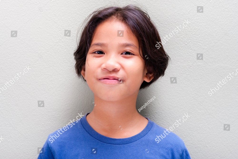 Headshot of nine years old Thai girl in blue t-shirt stand at the light ...