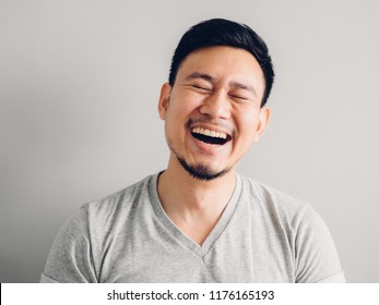 Headshot photo of Asian man with laugh face. on grey background.