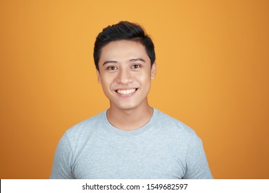 Headshot Photo Of Asian Man With Smiling Face On Orange Background.