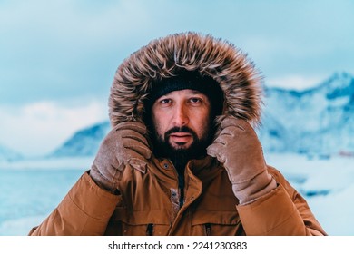 Headshot photo of a man in a cold snowy area wearing a thick brown winter jacket and gloves. Life in cold regions of the country.