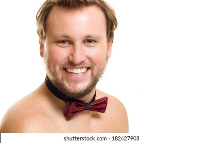 Headshot photo of white Caucasian male with a beard, blue eyes and brown hair. He is shirtless wearing a bowtie and looking very happy.