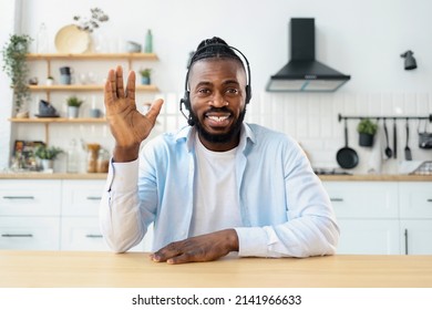 Headshot portrait of African American man in headset using laptop computer webcam for chatting online, video call concept, greets, looking at the camera and smiling friendly - Powered by Shutterstock