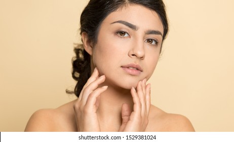 Headshot Portrait Of Beautiful Ethnic Naked Young Woman Isolated On Orange Brown Studio Background With Healthy Skin, Pretty Millennial Indian Girl Look At Camera Satisfied With Good Skincare Routine