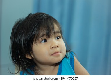 A Headshot Portrait Of A Cheerful Baby Asian Woman, A Cute Toddler Little Girl With Adorable Bangs Hair, A Child Wearing A Blue Vest Smiling And Not Looking At The Camera.