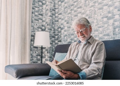 Headshot portrait close up of old happy and relaxed man sitting reading a book at home. Mature male person enjoying free time having fun indoor. - Powered by Shutterstock