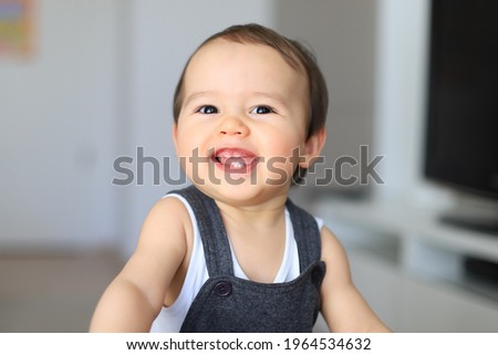 Headshot portrait of cute smiling baby with first milk teeth. Mixed race Asian-German infant laugh and having fun at home. Happy and healthy child.kid about 9-10 months old.