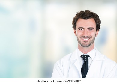 Headshot Portrait Of Friendly Young Male Doctor Smiling Standing In Hospital Hallway Clinic Office Windows Background 