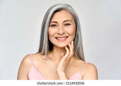 Headshot portrait of gorgeous happy middle aged mature asian woman, senior older 50 year lady looking at camera touching her face isolated on white. Ads of lifting anti wrinkle skin care, spa. - Shutterstock ID 2114933036