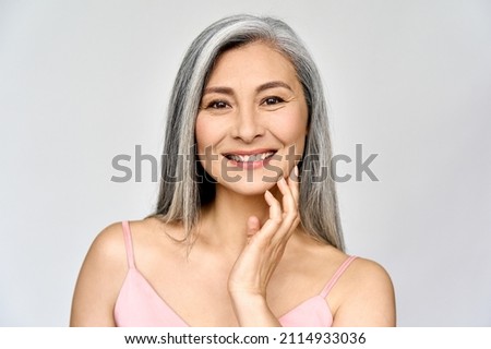 Headshot portrait of gorgeous happy middle aged mature asian woman, senior older 50 year lady looking at camera touching her face isolated on white. Ads of lifting anti wrinkle skin care, spa.