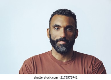 headshot portrait of a handsome bearded mid adult thoughtful man looking at camera against gray background studio shot