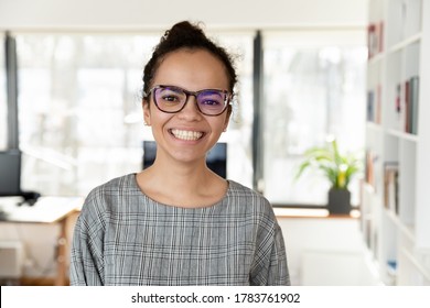 Headshot portrait of happy african American businesswoman in glasses look at camera pose in office, smiling biracial young female employee in spectacles show leadership and success qualities