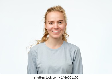 Headshot portrait of happy blonde girl in blue pulover smiling looking at camera. White background. Positive facial human emotion.