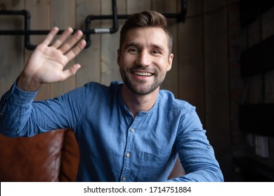 Headshot Portrait Of Happy Caucasian Young Man Sit In Cafe Wave Greeting Talking On Video Call, Smiling Millennial Male Have Fun Speaking Online Using Gadget Engaged In Internet Dating Service