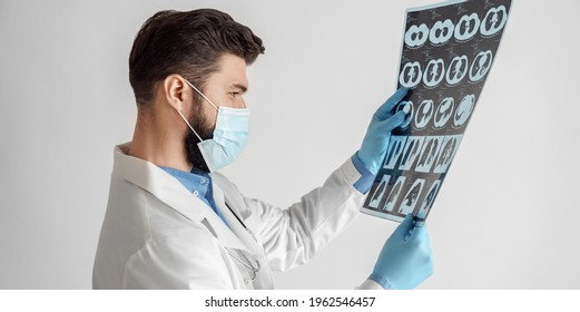Headshot portrait of male doctor neurologist physician or oncologist examining lungs x-ray computerized tomography scan. Side view studio shot on white background. Medical diagnosis concept