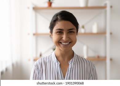 Headshot Portrait Of Pretty Smiling Millennial Female Of Indian Ethnicity Housewife Student Employee In Casual Closing. Profile Picture Of Happy Young Mixed Race Lady Looking At Camera Posing At Home